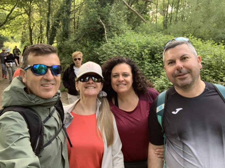 Selfie de cuatro peregrinos sonrientes en un bosque.
